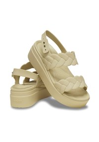 Ljusbeiga plattformssandaler med vävda remmar, texturerad fotbädd, justerbar ankelrem och upphöjd sula. Tillverkade av mjukt, flexibelt material.