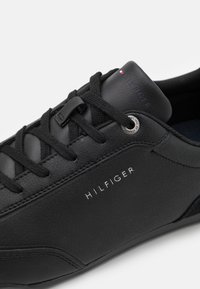 Černé kožené tenisky s tónovanými šněrovadly, stříbrnou očnicí a zvýrazněním loga. Texturované detaily na boku zvyšují jejich design.