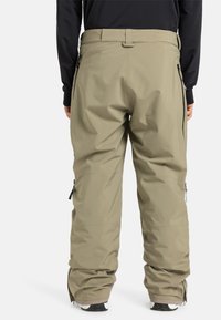 Pantalons de neige imperméables en olive clair. Comprend une coupe décontractée, des poches zippées et des poignets renforcés. Texture lisse avec une finition mate.