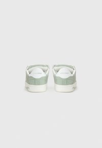 Des baskets en daim vert présentent une semelle en caoutchouc blanche et des accents blancs contrastants au niveau du talon et de la languette, ornés de la marque "etnies".