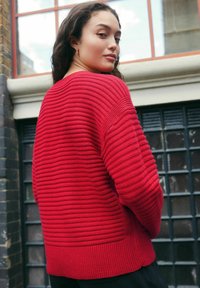 Rødstribet strikket sweater med en afslappet pasform, der har ribbede cuffs og kant, struktureret mønster og design med åben ryg.