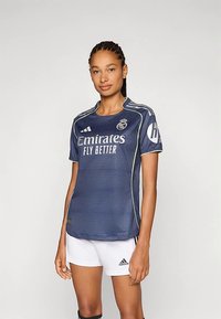 Tumesinise spordisärgi valmistatud hingavast materjalist, millel on tekstureeritud muster, valged logod ja kontrastne hele ääris. Sobitatud valgete pükstega.