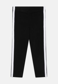 Leggings negras de corte ajustado, con rayas laterales blancas. Fabricados en una tela suave, con una cintura elástica para mayor comodidad.