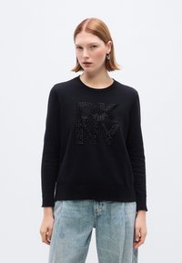Maglione nero in tessuto lavorato a maglia con logo "DKNY" decorato con rhinestones. Maniche lunghe e polsini a costine completano il design.