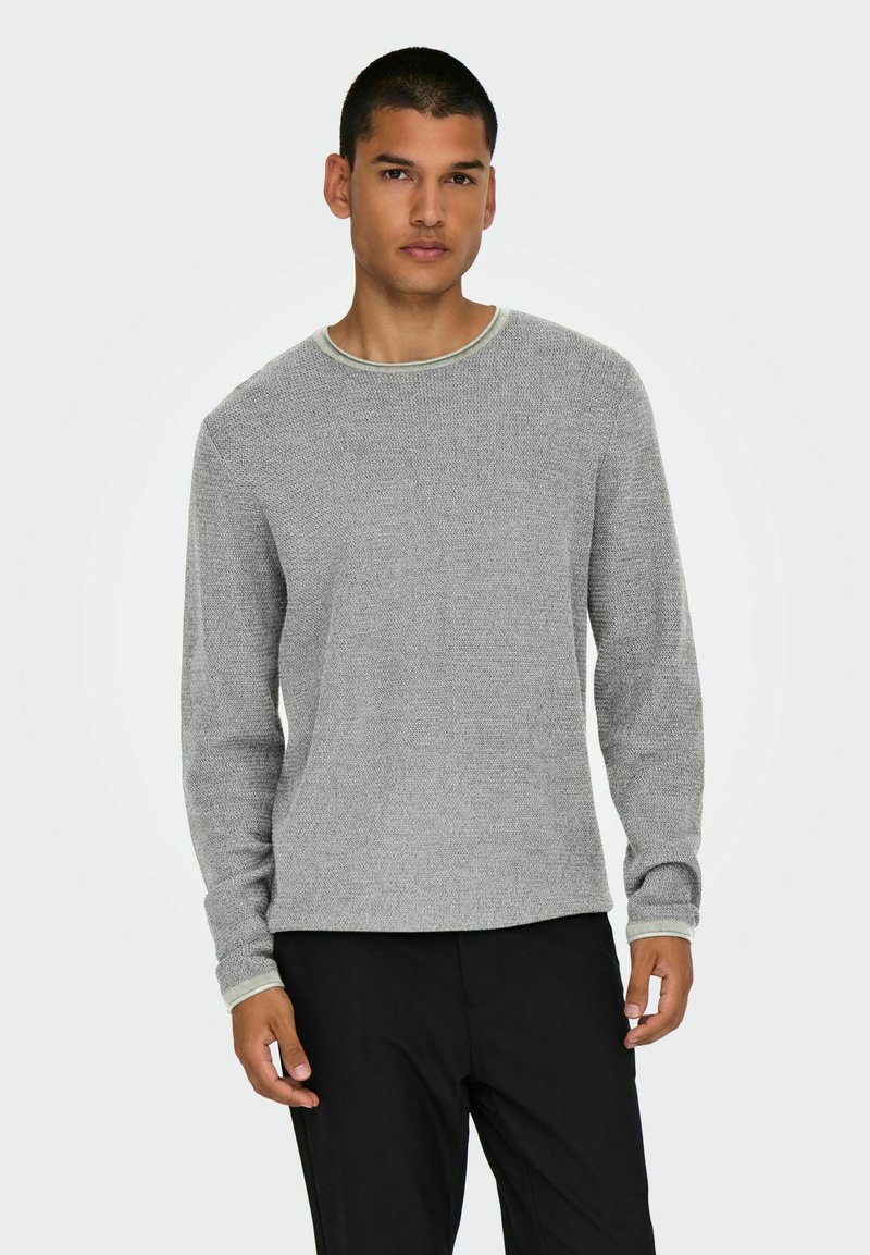 Grijze gebreide sweater met lange mouwen, ronde hals en contrasterende lichtgrijze afwerking bij de kraag en manchetten. Zachte textuur, ontspannen pasvorm.