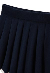 Jupe plissée marine avec une taille côtelée. Fabriquée en tissu doux, présentant des plis profonds qui créent une apparence structurée.