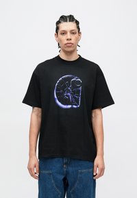 Svart bomulls-T-skjorte med et stort, grafisk motiv i blått og lilla på forsiden. Designet har en spiralform med en sirkulær aksent.