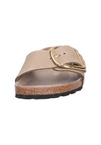 Sandal in tinta beige con una fascia ampia, dettagli in oro, soletta in sughero e suola in gomma nera con texture. Adatto per un look casual.