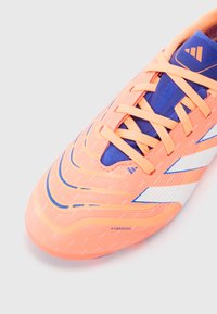 Bright orange and blue cleat with laces, white accents, and "HYBRIDFEEL" text on the toe area shown on a plain background.