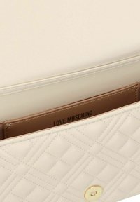 Portafoglio in ecopelle trapuntata beige con hardware dorato, dotato di chiusura a scatto e dettaglio del logo "LOVE MOSCHINO" all'interno.