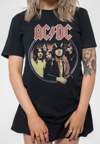 Black cotton t-shirt featuring AC/DC graphic with band members in a circular design. Short sleeves and relaxed fit. No notable texture or patterns.
