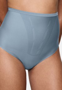 Sömlös ljusblå underkläder med hög midja, som bärs på en persons midja och övre lår, och framhäver en slät passform och tygstruktur.