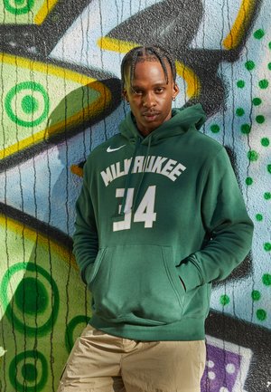 Zöld kapucnis pulóver, amelyen fehér "MILWAUKEE" felirat és "34" szám található. Simaságával kiemelkedő anyagból készült, kanguru zsebből és húzózsinórral ellátott kapucniból áll.