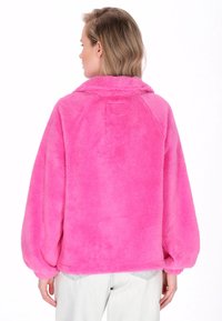 Rosa Kunstpelz-Pullover mit Kragen, Ballonärmeln und weicher Textur, mit einfachem Design und ohne sichtbare Verschlüsse oder Muster.