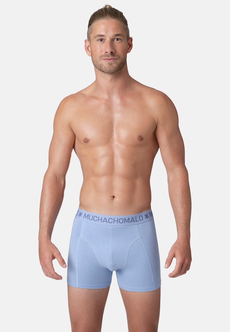 Boxers de color azul claro hechos de una tela elástica; cuentan con una banda suave en la cintura con el logo "MUCHACHO". Textura suave y diseño ajustado.