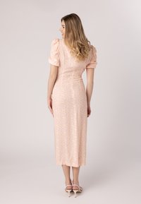 Vestido midi rosa con mangas abullonadas, tejido texturizado y un sutil patrón floral. Silueta ajustada con un acabado suave y cremallera en la parte trasera.