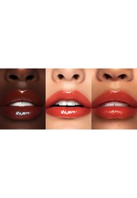 Tre coppie di labbra che mostrano diverse tonalità di rossetto arancione. Le texture variano da opaco a lucido, con toni di pelle diversi.