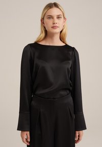 Blusa nera in satin con scollo a barca, maniche lunghe e spalle leggermente a sbuffo, caratterizzata da una texture liscia e morbida e un'elegante caduta.