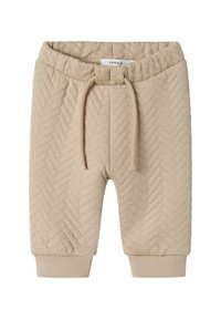 Pantalones cortos de punto beige con un patrón de espiga, cinturilla elástica con cordón de ajuste y puños acanalados en el dobladillo. Textura suave.