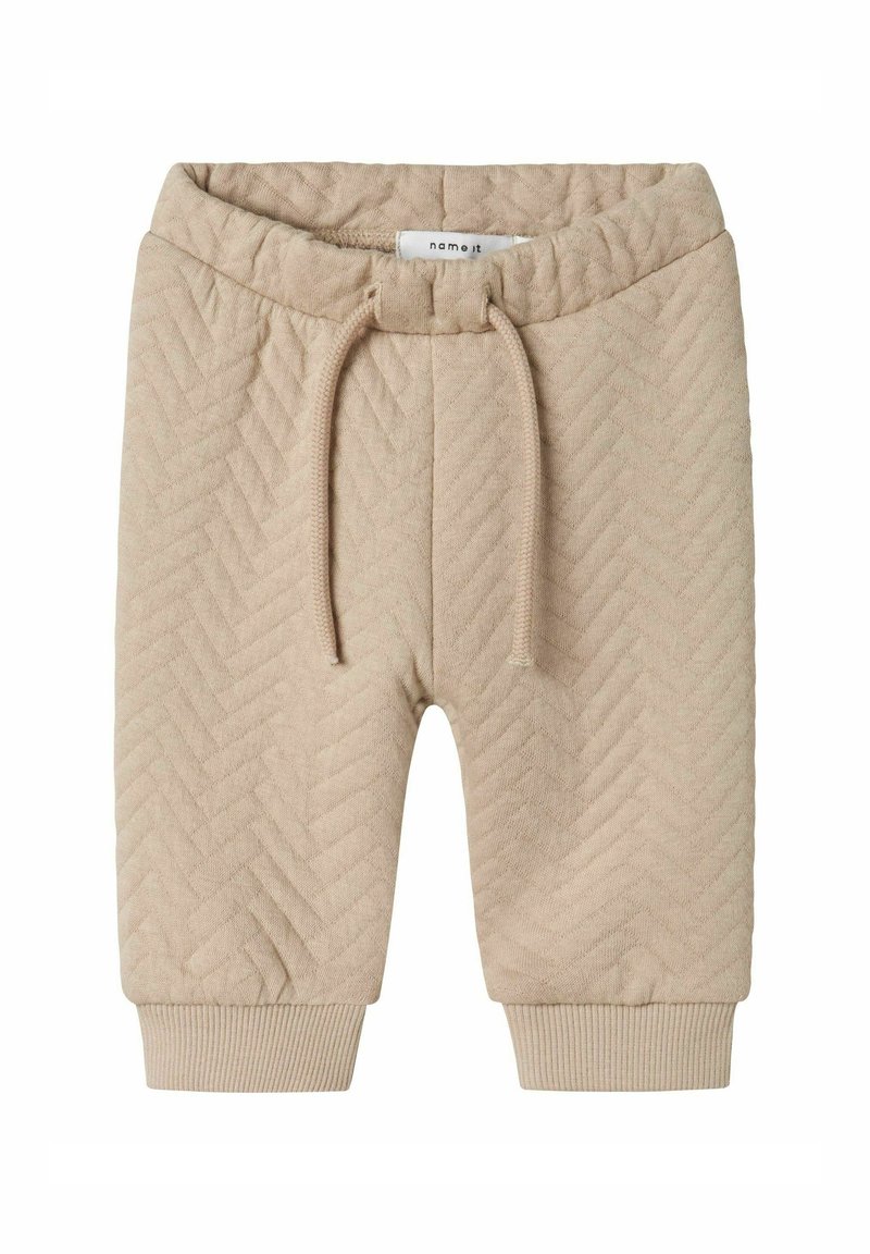 Pantalones cortos de punto beige con un patrón de espiga, cinturilla elástica con cordón de ajuste y puños acanalados en el dobladillo. Textura suave.