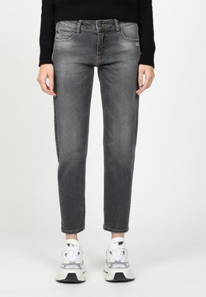 Graue Jeans aus Denim mit schlanker Passform, fünf Taschen und dezentem Farbverlauf. Kombiniert mit weißen und silbernen Sportschuhen.