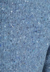 Gebreide trui stof in verschillende tinten blauw, met witte en donkere spikkels. Getextureerde uitstraling met een zachte, gezellige afwerking.