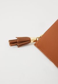 Pochette in pelle marrone con una superficie liscia, dotata di una cerniera in metallo dorato e un elegante fiocco marrone decorativo.