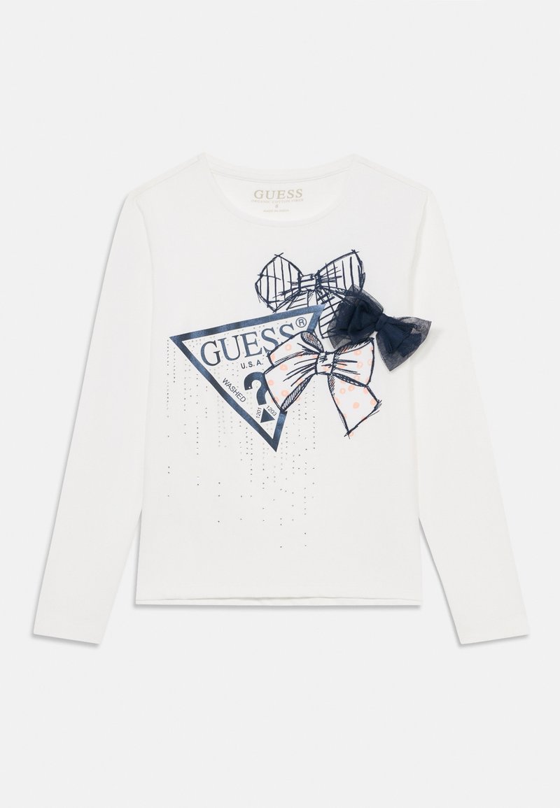 Hvit langermet T-skjorte med en trekantet grafikk som har Guess-logoen, to sløyfer i marineblått og mønstret stoff, samt glitrende detaljer.