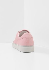 Růžové kožené tenisky s oblým zadním dílem, bílou gumovou podrážkou a texturovanými akcenty. Jednoduchý design s minimem švů.