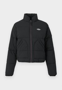 Črna puffer jakna z visokim ovratnikom, zadrgo, dvema sprednjima žepoma in prešito teksturo. Ima logotip na prsih in vijolično zadrgo.