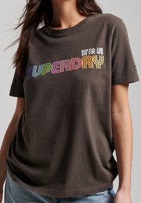 Czarna szara koszulka bawełniana z kolorowym napisem "SUPERDRY" w falistym kroju; krótki rękaw i luźny krój.