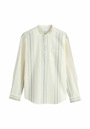 Długa kremowa koszula z zielonymi pionowymi paskami, stojącym kołnierzem, plisą na guziki i pojedynczą kieszenią na piersi. Miękka, teksturowana tkanina.