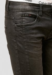 Zwarte denim jeans met een slanke pasvorm, voorzien van een voorvak met branding, contrasterende stiksels en een witte Calvin Klein tailleband.