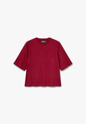 Rotes kurzärmliges Rundhals-T-Shirt aus Baumwolle mit einem grünen Etikett im Kragen auf einem weißen Hintergrund.