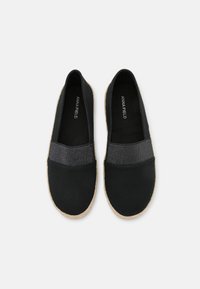 Zapatos de espadrilles negros con una banda elástica negra texturizada en la parte delantera; suela de yute natural con un diseño plano y puntera redonda.