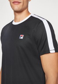 Svart atletisk t-shirt med vita axelränder och logotyp. Tillverkad av texturerat tyg, med rund halsringning och korta ärmar.