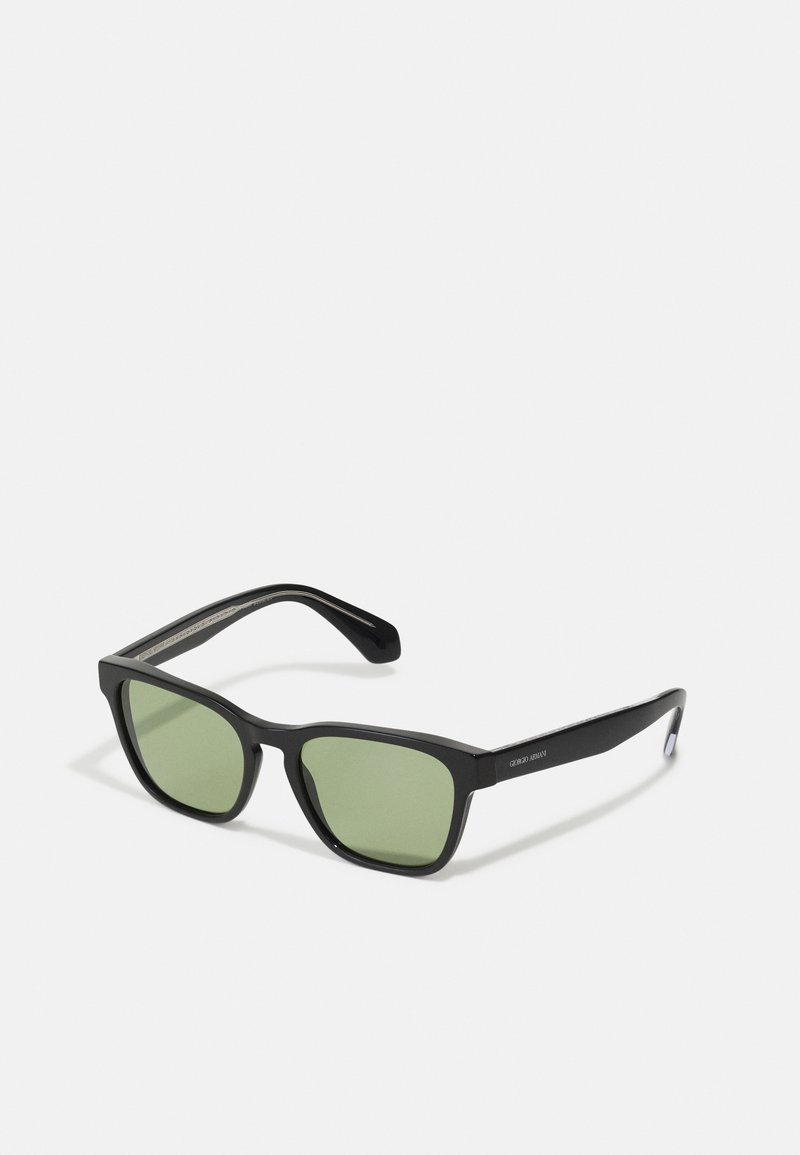 Ochelari de soare negri cu lentile verzi. Design cu ramă pătrată, realizată din material mat. Branding notabil pe braț și textură netedă.