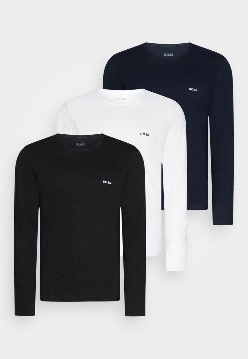 Trois t-shirts à manches longues en noir, blanc et marine. Matériau en coton avec logo sur la poitrine, encolures arrondies et coupe droite.