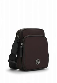 Brown rectangular crossbody bag with two zippered compartments, black adjustable strap, and silver double "B" logo on front pocket.