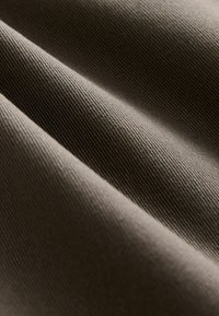 Tissu texturé de couleur brun doux, présentant des crêtes visibles et une surface douce. Le matériau semble durable et épais, avec de subtiles variations.