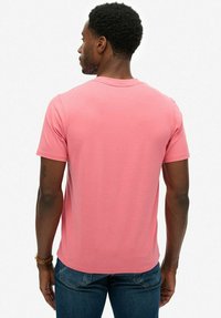 Roze katoenen t-shirt met korte mouwen en een ronde hals, gezien vanuit de achterkant. Eenvoudig ontwerp, gladde textuur en getailleerde pasvorm.