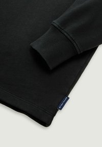 Zwarte katoenen sweatshirt met ribgebreide boorden en zoom. Beschikt over een klein blauw label met "Tom Tailor" aan de zijkant, heeft een gladde textuur en een klassiek ontwerp.