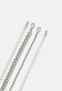 Sølvm metal kæder i forskellige tykkelser og led. Inkluderer en stor curb kæde, en snoet kæde og to tynde kæder med låsehardware.