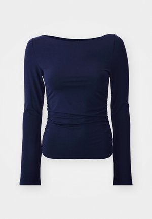 Haut long à manches en tissu doux et extensible, de couleur marine, avec un col rond et un détail froncé sur les côtés, offrant une silhouette ajustée.