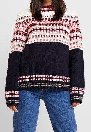 Pull en tricot bleu marine avec un motif géométrique rouge, blanc et noir. Il présente un col rond, des manches longues et des bords côtes aux poignets et à l'ourlet.