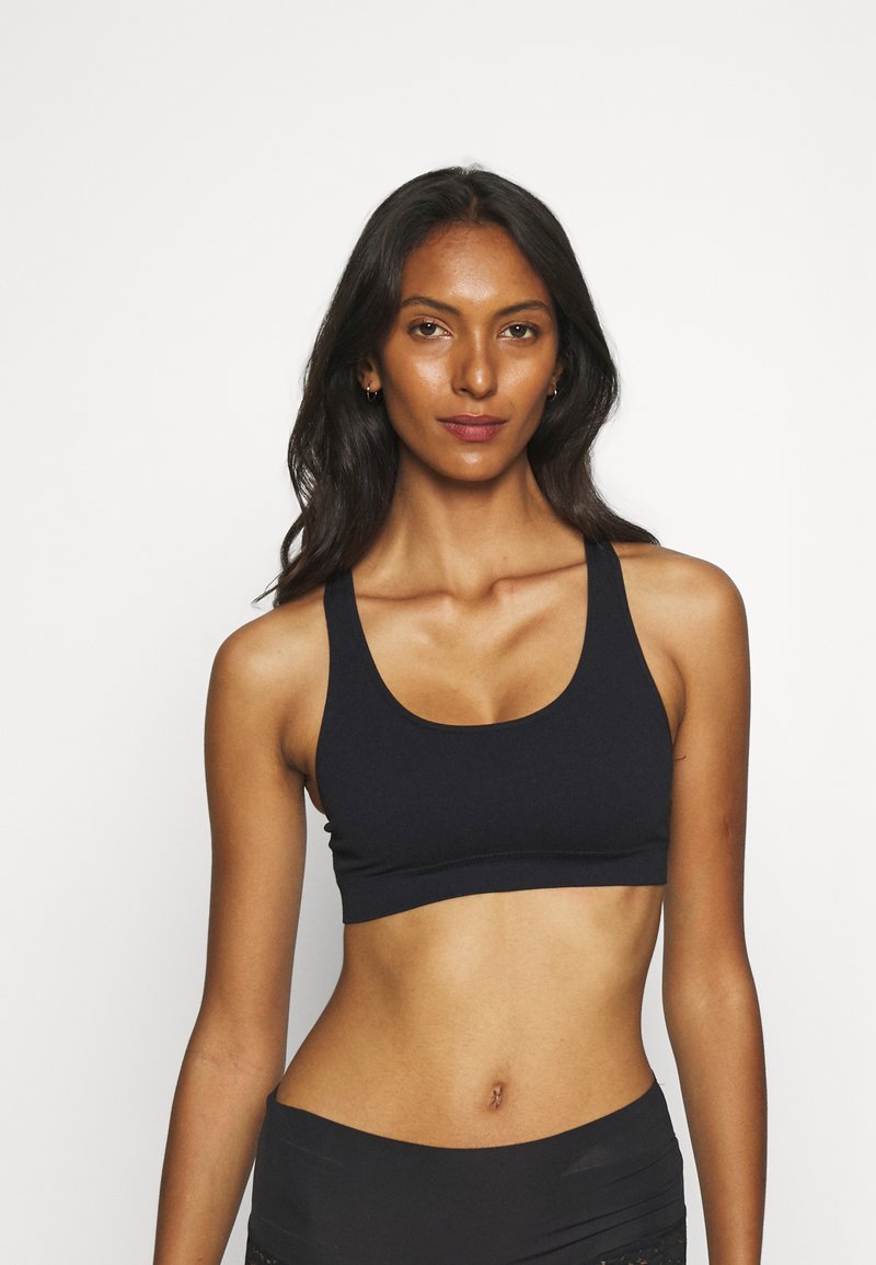 Black sports bra with a scoop neckline and wide straps. Made of smooth, stretchy fabric, designed for a fitted and comfortable silhouette.