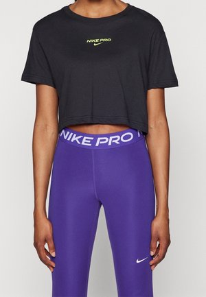 Person trägt schwarzes, kurz geschnittenes Nike Pro T-Shirt und hoch taillierte lila Nike Pro Leggings mit Logo an Taille und Knöcheln.