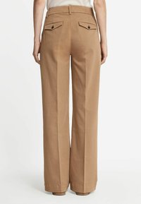 Spodnie o szerokich nogawkach w kolorze brązowym wykonane z bawełny, z wysokim stanem, dwiema tylne kieszeniami z guzikami oraz wyraźnymi zmarszczeniami z przodu i z tyłu.