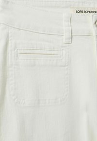 Material denim alb, dotat cu un buzunar plat pe spate, cu o deschidere dreaptă, detalii de cusătură subtile și o etichetă cu marca la talie.