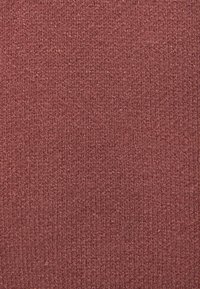 Gestructureerde stof in een rijke bordeauxrode kleur, met een gebreid patroon met zichtbare draden en een gelijkmatige, matte afwerking.